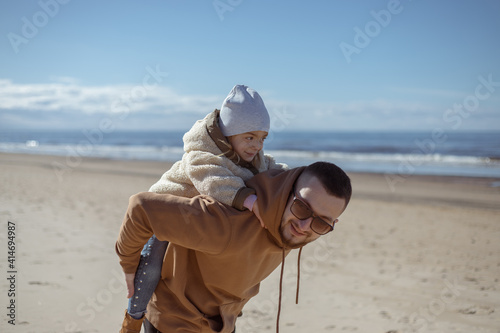 Father with daughter having fun on the beach at the day time.Concept of friendly family.