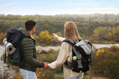 Couple of travelers with backpacks enjoying beautiful view near mountain river. Autumn vacation © New Africa