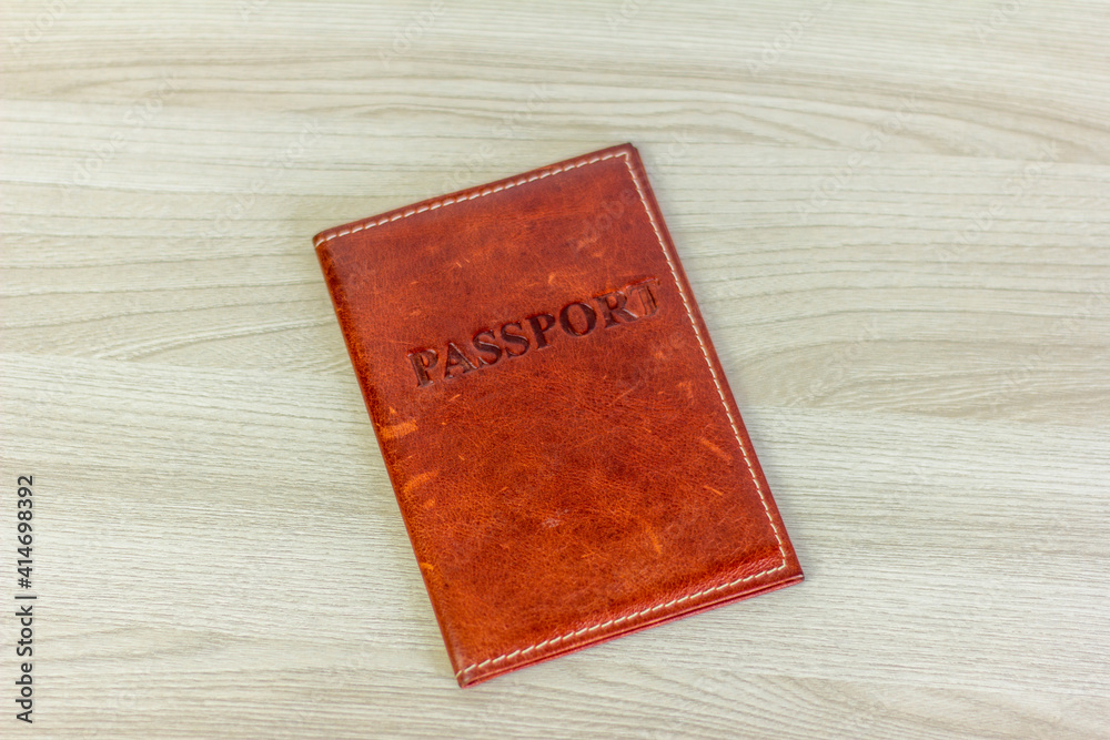 Passport in a brown leather cover on the table.