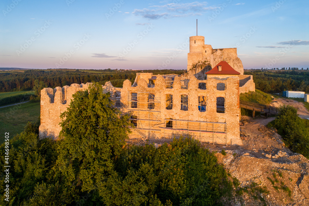 Rabsztyn, Poland. Ruins of medieval royal castle on the rock in Polish Jurassic Highland. Aerial view in sunrise light in summer. Renovation and archeological works in progress