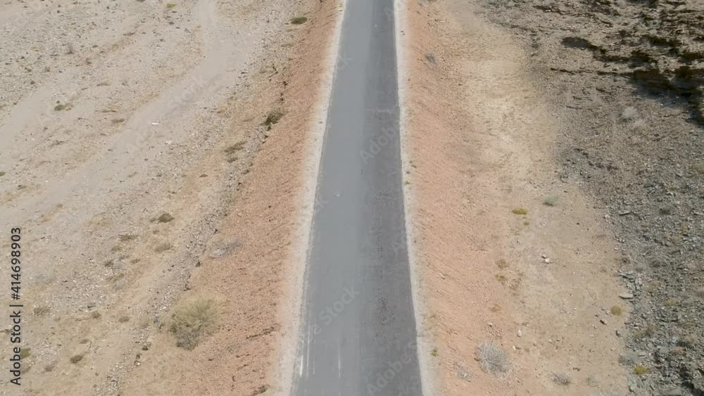 Tarmac road snaking through a desert landscape with rocky hills on both sides of the road camera rising up Aerial Tarmac road snaking through a desert landscape with rocky hills on both sides of the road camera rising up Aerial
