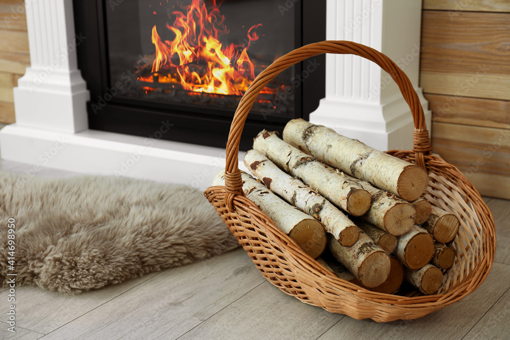 Firewood in wicker basket near burning fireplace indoors Stock Photo |  Adobe Stock