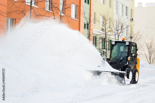 small tractor cleans snow from the street