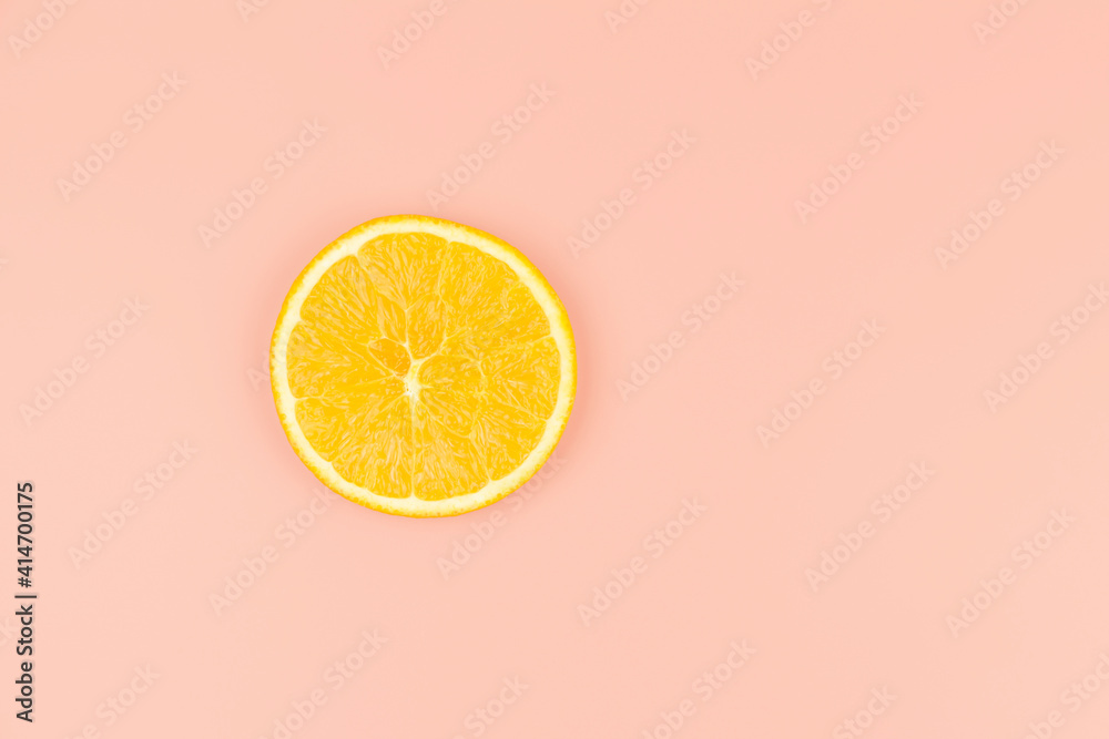 bright round orange slice on peach background, healthy food concept