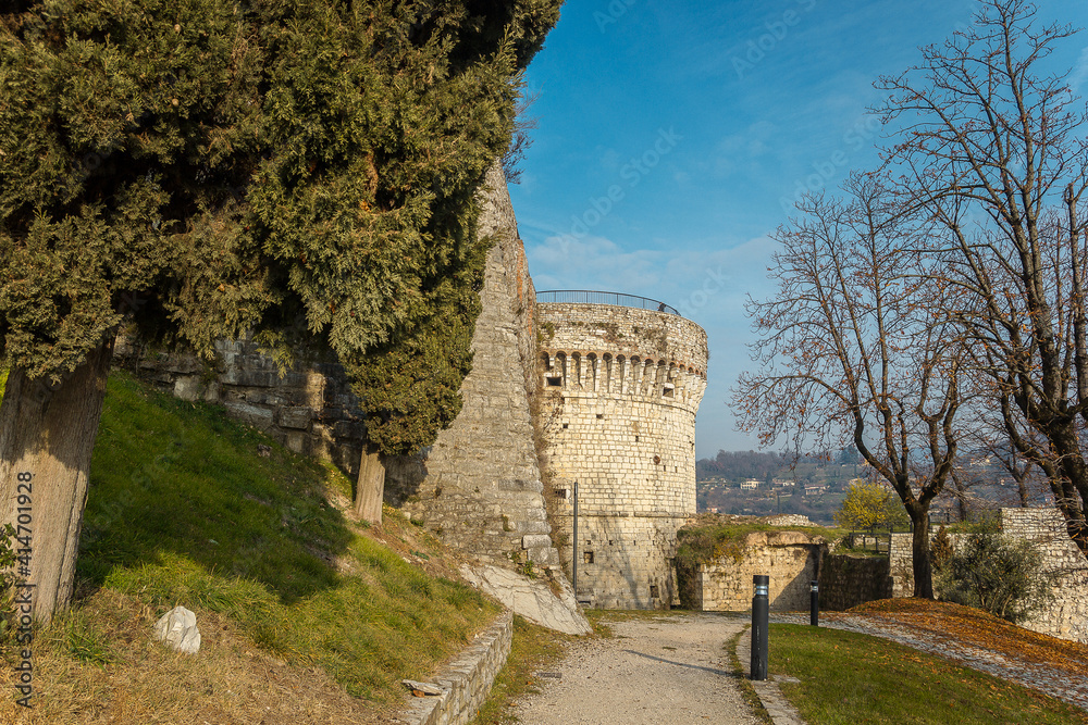 Part of the castle of the city of Brescia on a sunny winter day. A view on the tower. Castello di Brescia, Lombardy, Italy. Medieval castle with battlements, a tower, drawbridge and ramparts. 