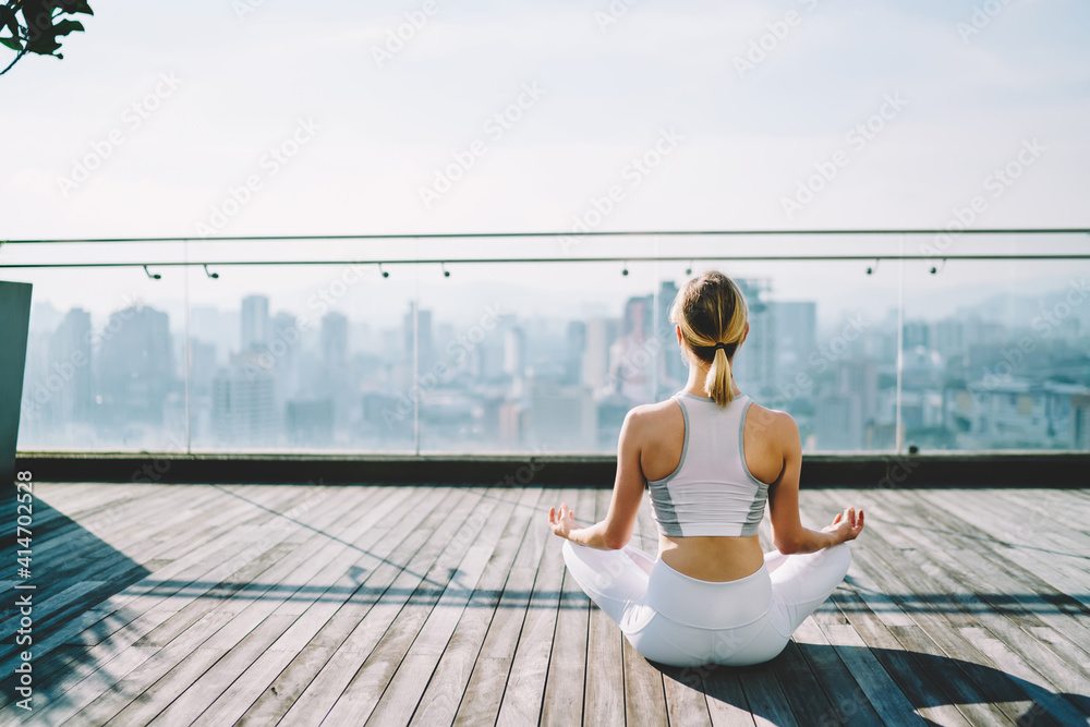 Woman relieving stress in lotus pose on terrace