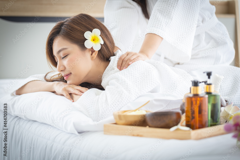 Beautiful Asian young women enjoying massages and spa treatments at home. Smiling long hair young girl in spa clothes with friends doing DIY spa by herself at home in white bedroom. Beautiful Asian young women enjoying massages and spa treatments at home. Smiling long hair young girl in spa clothes with friends doing DIY spa by herself at home in white bedroom.