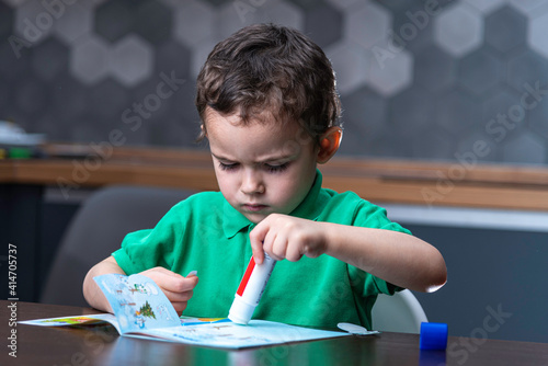 Boy’s gluing application. Serious boy’s is making handicraft.