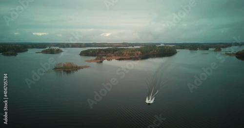 Fast solo Yacht sailing in calm river waterway with scattered islands, fall season photo