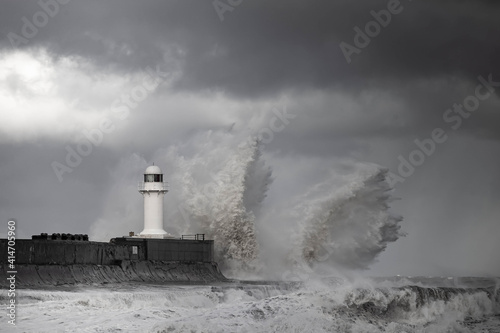 Lighthouse being battered by forceful winter storm waves crashing