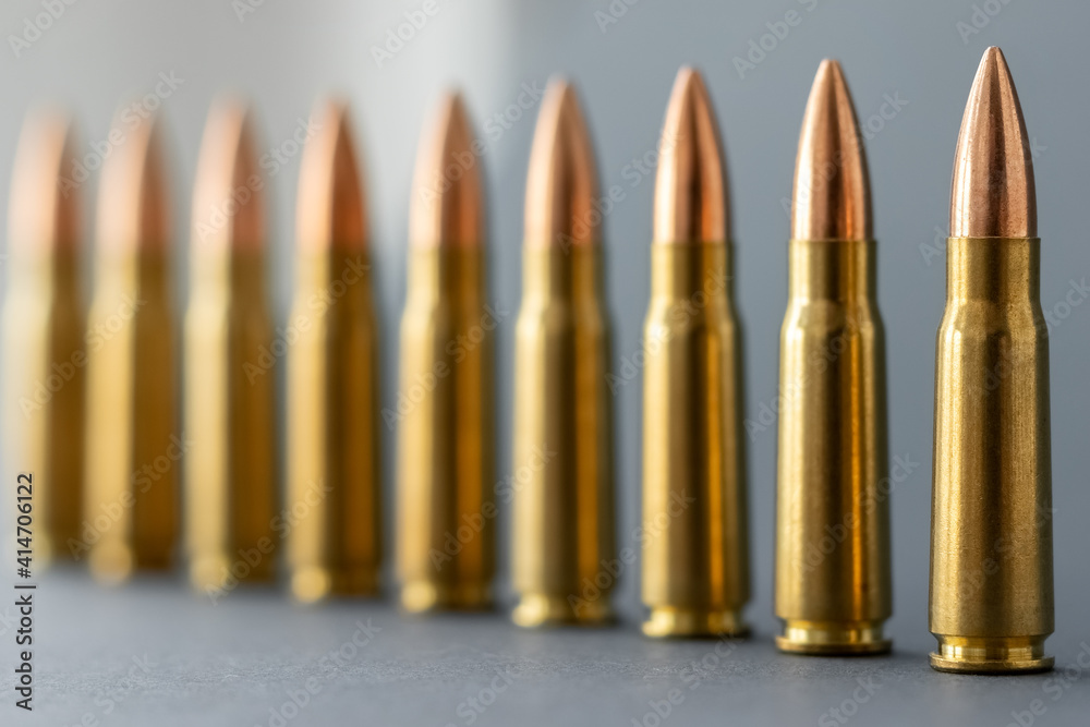 Bullets on gray background. Cartridges 7.62 caliber for Kalashnikov assault rifle closeup. Selective focus on foreground Bullets on gray background. Cartridges 7.62 caliber for Kalashnikov assault rifle closeup. Selective focus on foreground
