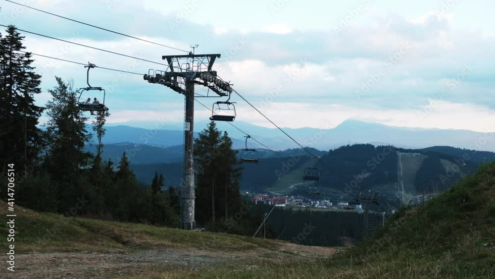 Ski lift moving with hardly any tourists during lockdown. Empty seats in cable cars. View from the top of the hill. Beautiful scenic summer landscape, evening in the blue mountains, forest around. Ski lift moving with hardly any tourists during lockdown. Empty seats in cable cars. View from the top of the hill. Beautiful scenic summer landscape, evening in the blue mountains, forest around.
