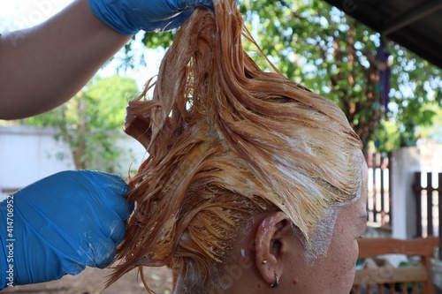 Asian girl Do a pretty fashionable hair dye in gold at home on vacation.