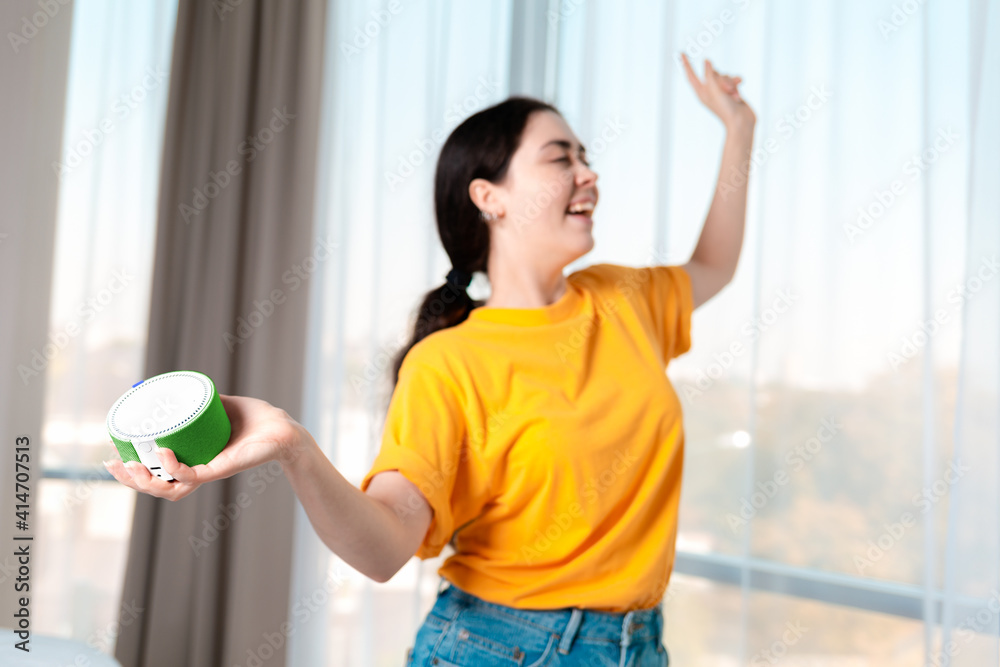 Portrait of a young girl holding a portable smart speaker that plays music and dances. The concept of modern gadgets Portrait of a young girl holding a portable smart speaker that plays music and dances. The concept of modern gadgets