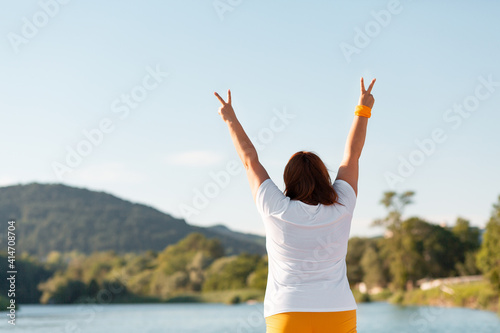 The overweight woman raised the top of her hand and pointed her fingers at the victory sign. The view from the back. Copy space