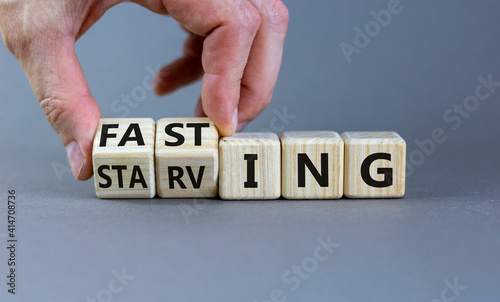 Fasting or starving symbol. Doctor turns wooden cubes and changes the word 'starving' to 'fasting'. Beautiful grey background, copy space. Healthy eating, medical and time to fasting concept.