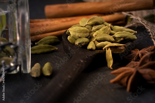 cardamom together with vanilla and glass packaging on a black background. Still life of colorful spices suitable for cookbook, cookbook and for background