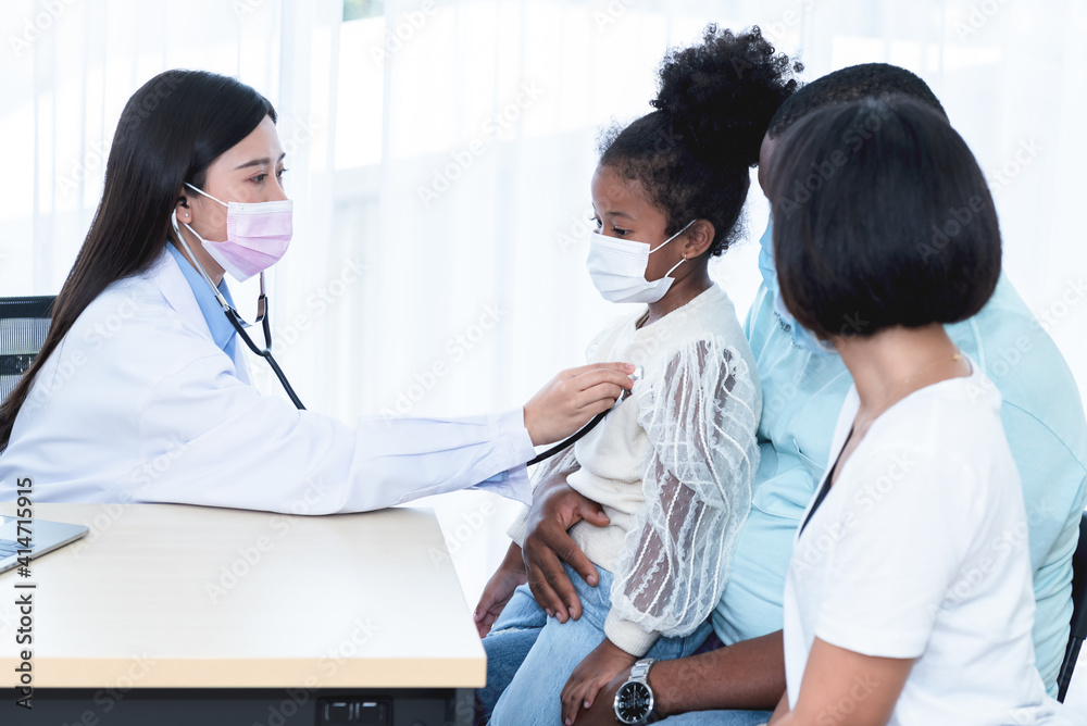 Fototapeta premium Asian woman doctor wearing surgical mask and using a stethoscope, checking the respiratory system and heartbeat Of a 5-year-old girl, who is half African half Thai, to family and health care concept.