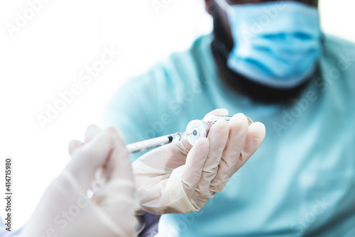 Blurred soft images  Doctor holding Covid-19 vaccine in the hands  who are preparing for vaccination For patient  with blurred soft an African American background  to health care and vaccine concept.