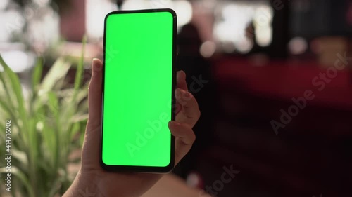 Close up of a woman's hand holding a mobile telephone with a vertical green screen in restaurant chroma key smartphone technology cell phone street touch message display hand