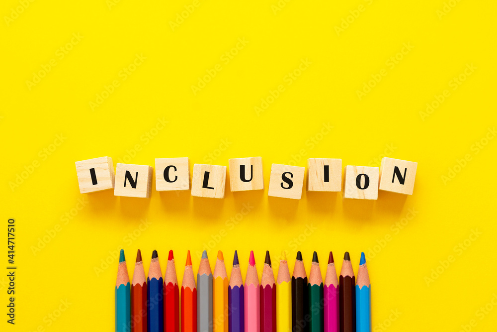 Inclusion concept word on wooden cubes and pencils on yellow background Inclusion concept word on wooden cubes and pencils on yellow background