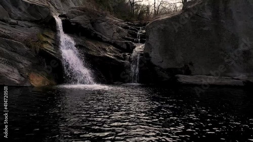 Sideways drone flight over some stones and a waterfall at daytime near photo