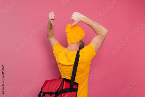 European bearded delivery man with box with food showing thumbs down on bag on pink background isolated