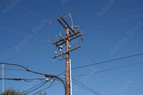Low angle view of an electricity distribution pylon and power lines under blue sky