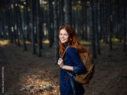 Happy woman hiker in the forest with a backpack on his back in autumn on nature