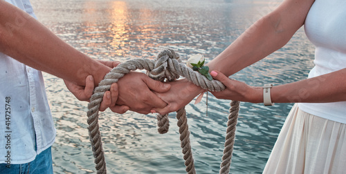 Foto Wedding ceremony handsbye, wedding anniversary, valentine's day tied in nautical rope handfasting vows, as a sign of eternal love and veneration