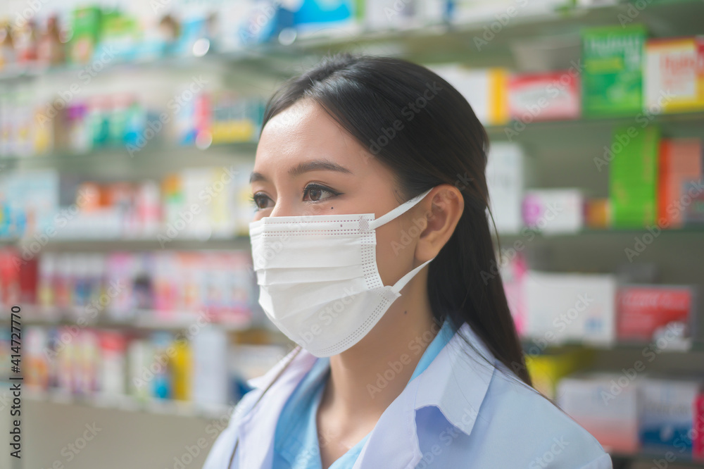 Portrait of asian woman pharmacist wearing a surgical mask in a modern pharmacy drugstore, covid-19 and pandemic concept.