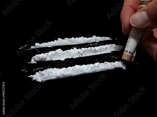 Man use 50 euro banknote to snorting cocaine drug powder lines on black table