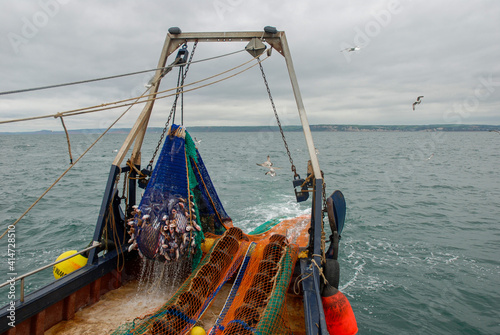 Photos A trawler hauls its trawl net cod end aboard, with a full catch