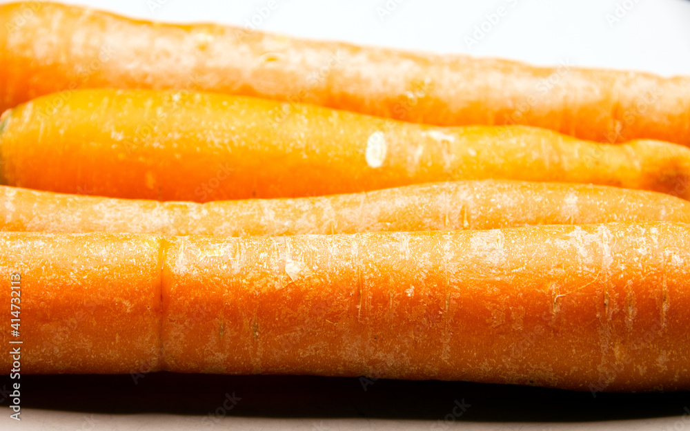 Four raw organic carrots on a white porcelain plate closeup Four raw organic carrots on a white porcelain plate closeup