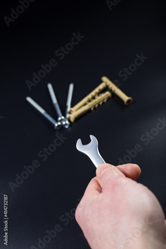 Hand holding wrench. Start building. Long dowelson background.