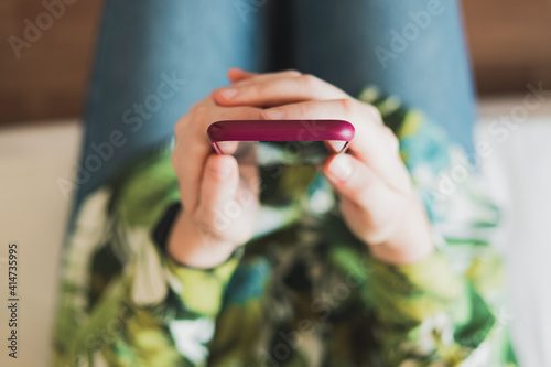 Mobile phone in woman's hands, shot from above with thin depth of field. Female person holding a smartphone in hands photo