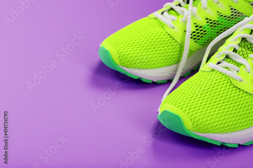 Green running shoes on a purple background.