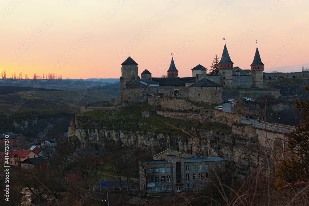 Obraz premium Awesome aerial landscape view of the old Kamianets-Podilskyi fortress. Panoramic sunset sky in the background. Famous touristic place and travel destination in Ukraine.Concept of landscape and nature