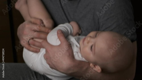Father lulling to sleep his little son. Toddler baby boy lying in father's arms. Father's day, parenthood concept.