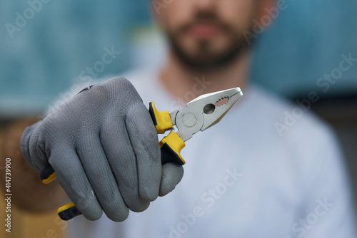 Necessary hand tool. Close up shot of hand of young repairman holding pliers photo
