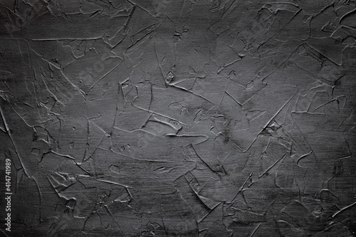 A ready-made textured black background with a vignette for subject and food photography. Black textured wall with negative space. Homemade background made with a spatula and textured putty. Copy space