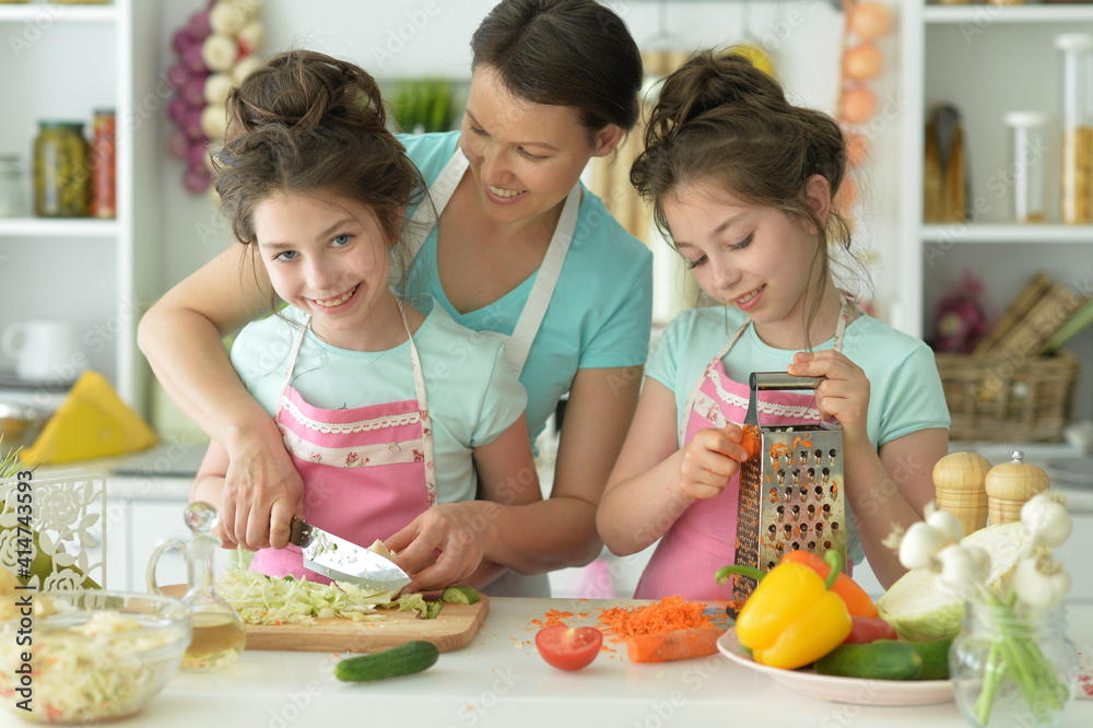 Cute happy girls coocking on kitchen with mother Cute happy girls coocking on kitchen with mother