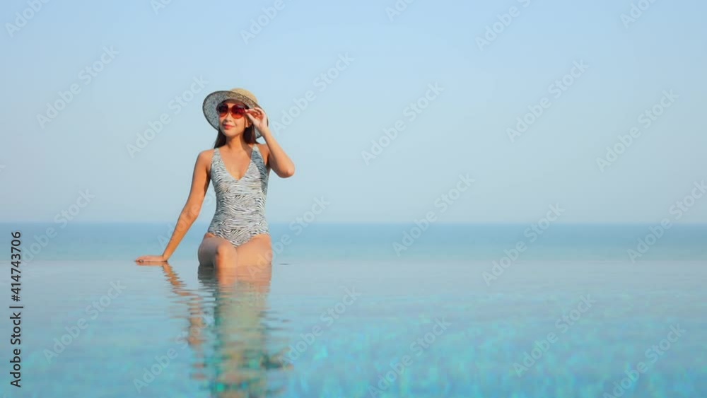 Beautiful asian woman sitting on the edge of the infinity swimming pool slow motion Beautiful asian woman sitting on the edge of the infinity swimming pool slow motion