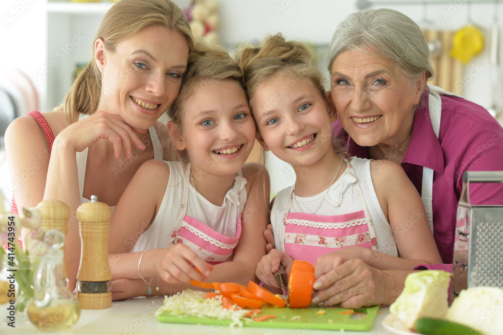 Cute girls with mother and grandmother preparing delicious fresh salad