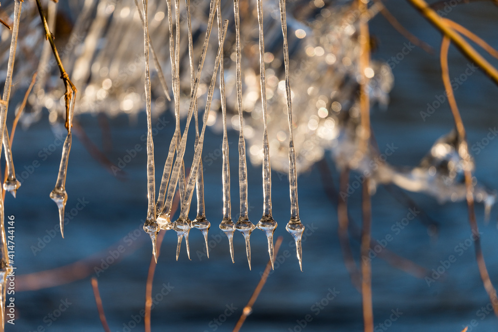 Light reflected through icicles at a river in winter time Light reflected through icicles at a river in winter time