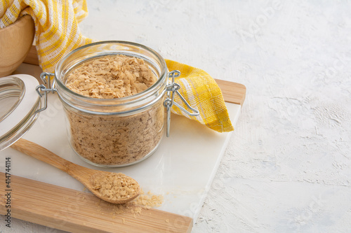 Flakes of Yellow Nutritional Yeast in a glass jar.