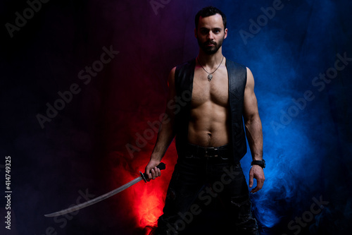 Ukrainian cossack posing with long sword isolated on black and smoked background photo