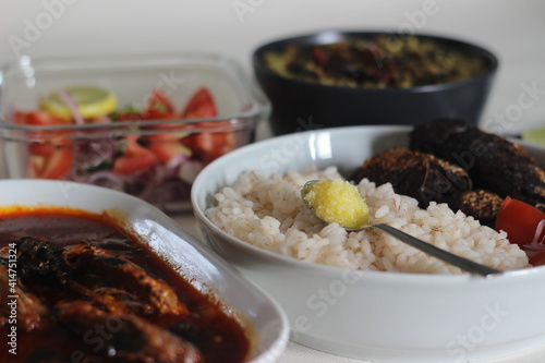 Kerala meals with red rice, sardines curry, sardine fry and coconut based green gram curry photo