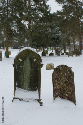 Snow covered landscape in Wymondham Abbey in Norfolk East Anglia grave yard people background walking dog in scene covered in white layer in freezing weather Winter 2021 lockdown covid-19 outbreak photo