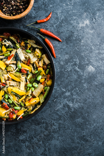 Fresh asian vegetables mix, Thai wok in a black pan on the black background with copy space. Healthy food